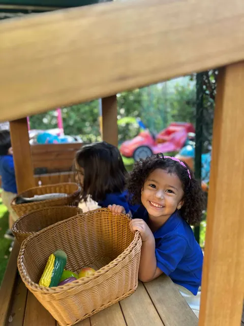 A girl peeking from behind a basket on the playground