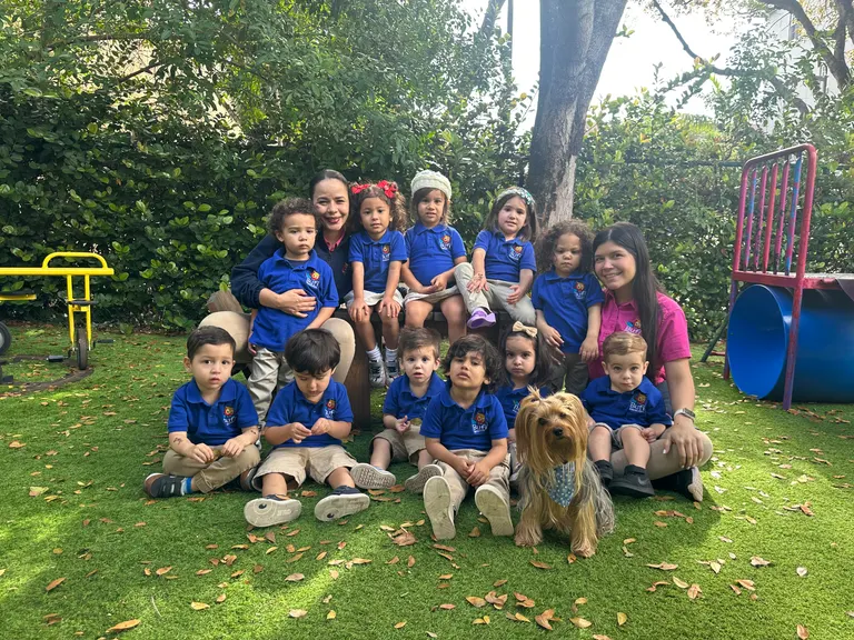 The whole class and their teachers sitting together on the grass